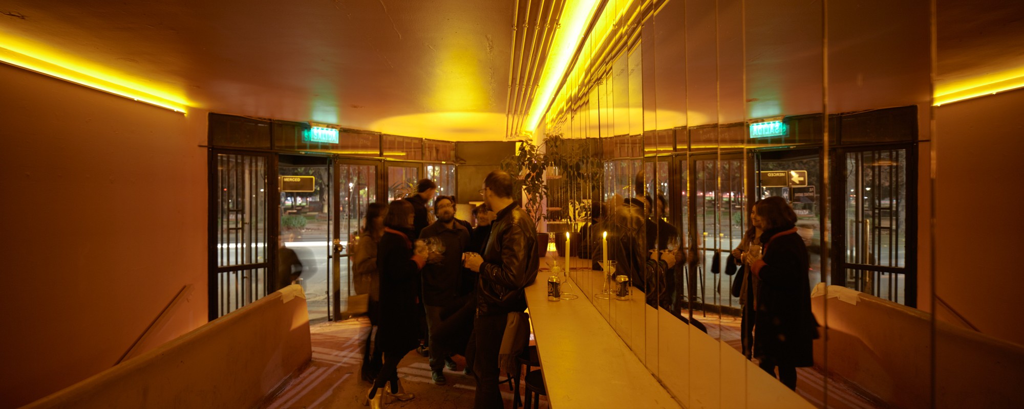 The yellow from the marquee outside is brought through the entrance to the club.